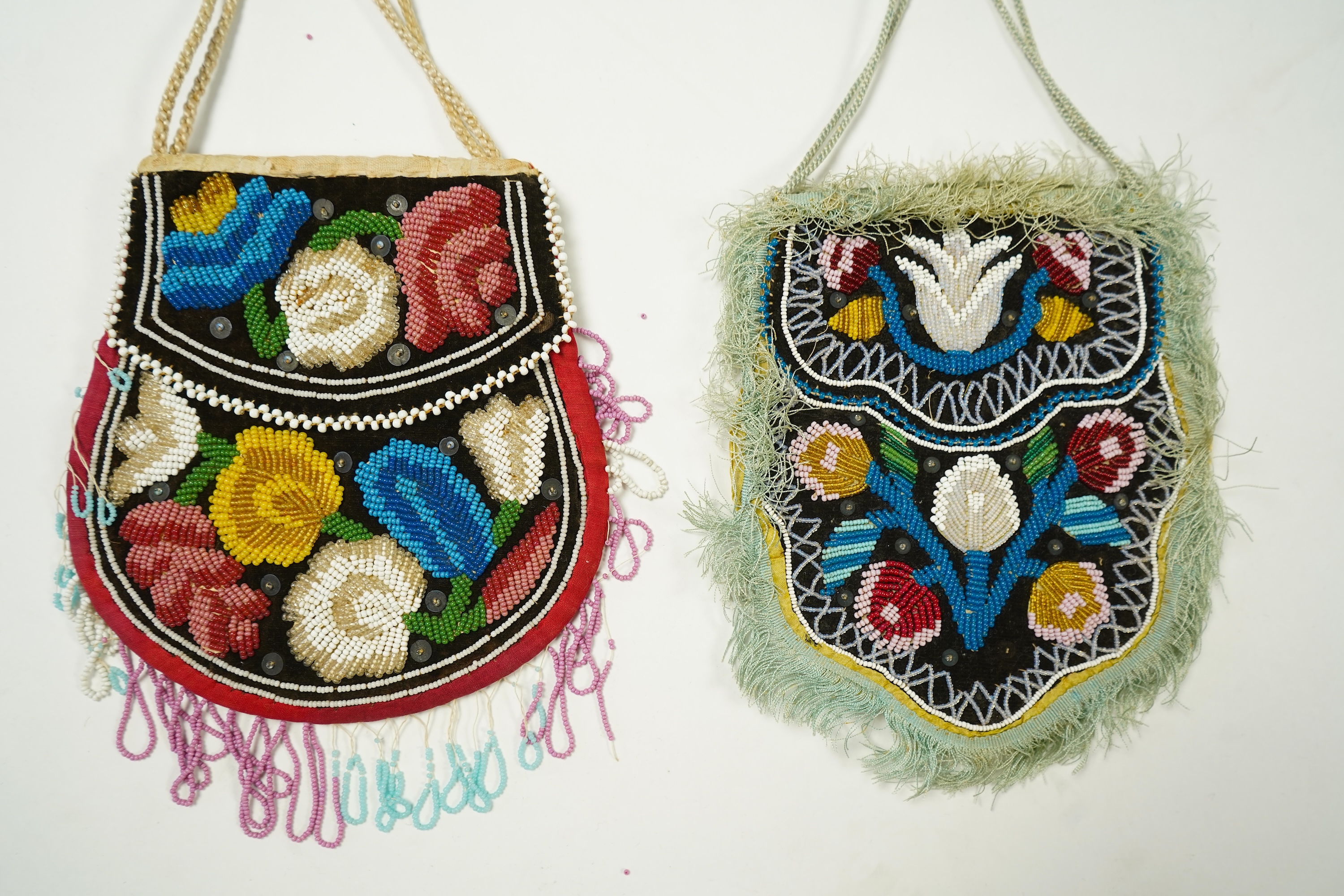 Two Native American Iroquois beaded bags. One edged with fine pale blue silk fringing, the other larger with bead worked fringing. Largest 16.5cm high. Condition - The blue fringed bag has a few sequins missing and the f